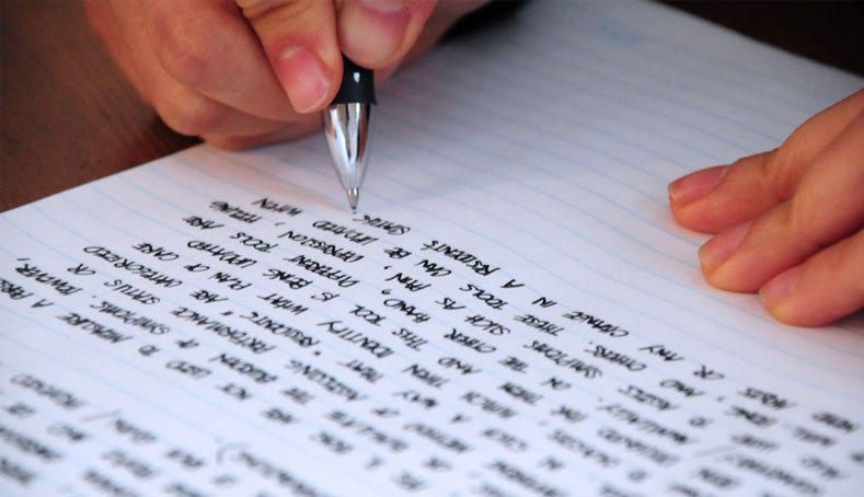 Person writing with a pen on a lined notebook with legible cursive handwriting, representing autobiography writing services.