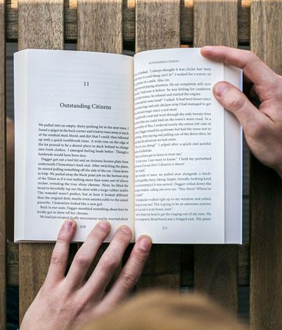 A person reading a book on a bench, highlighting the importance of book formatting services in enhancing reading experiences.