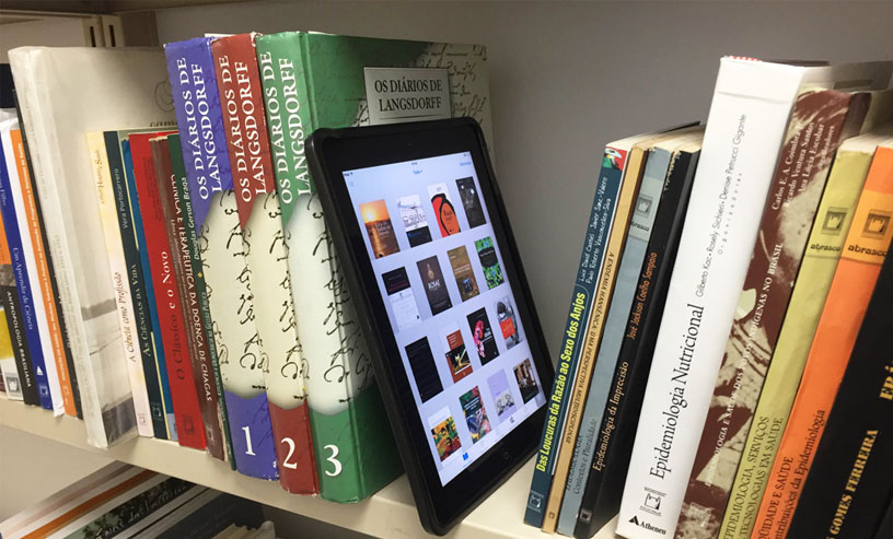 A tablet on a bookshelf with various books, emphasizing the availability of childrens ebooks for educational enjoyment.