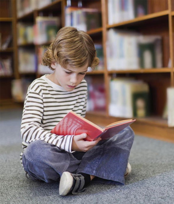 A young boy on the floor, deeply focused on a limited edition children's book, showcasing his love for reading.