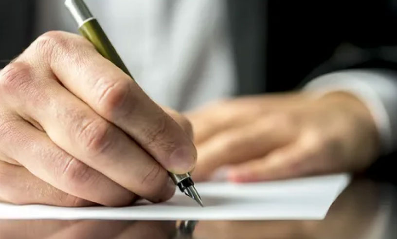 A person writes on paper with a pen, creating notes for an information ebook.
