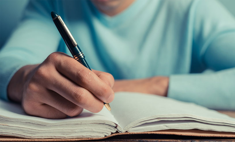 A man writing in a notebook, concentrating on writing non-fiction books and developing his ideas.