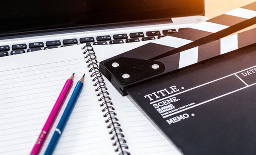 A wooden table with a clapperboard, laptop, and pencil, symbolizing essential tools for writing screenplay books.
