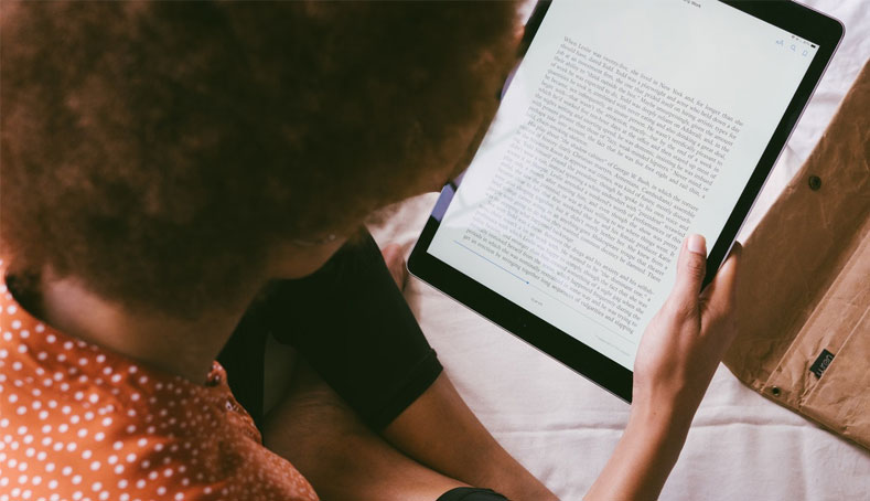 Woman focused on her tablet, exploring self-help ebooks, highlighting her commitment to self-improvement.